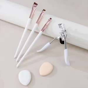 Professional makeup tool set including eyeliner brushes, eyelash curler, and soft puffs.