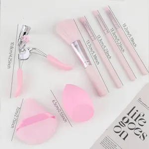 Pink makeup brush set with eyelash curler powder puff and beauty sponge detail view