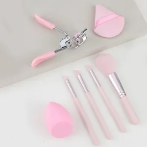 Pink makeup brush set with eyelash curler, beauty sponge, and powder puff for daily use.