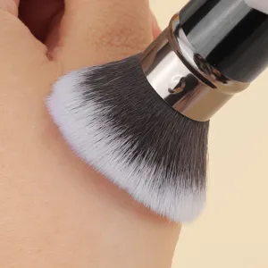 Makeup brush detail shot showing soft dual-color bristles and smooth metal handle texture.