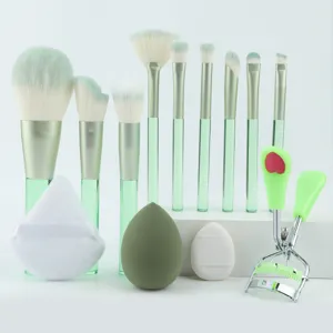 Detailaufnahme von Make-up-Pinseln mit grünen Griffen, weichen Schwämmen und Wimpernzange.
