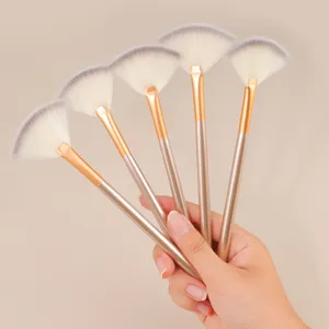 Detailed view of professional fan makeup brushes with soft synthetic bristles and gold handles.