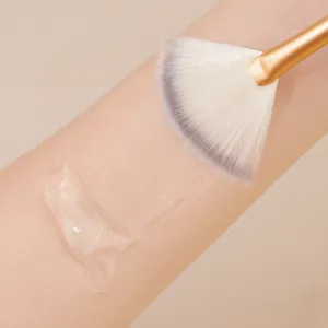 Close-up detail of the professional fan makeup brush applying clear gel texture on skin.