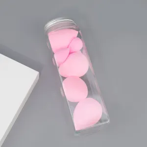 Detail shot of pink makeup sponges stored inside a clear plastic cylinder container with a lid.
