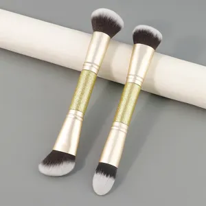 Pinceau de maquillage double embout avec poignée pailletée dorée pour fond de teint.