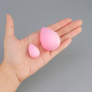 Close-up of small and large pink teardrop makeup sponges displayed on hand for easy blending.