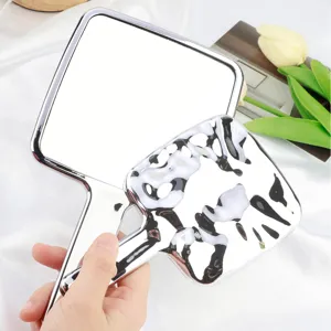 Détail du miroir de maquillage à main avec finition métal liquide unique et manche élégant.