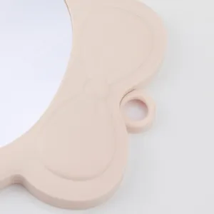 Nahaufnahme eines niedlichen rosa schleifenförmigen Make-up-Spiegelrahmens mit Aufhängung.