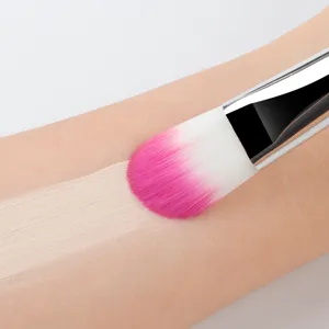 Gros plan d'un pinceau de maquillage plat appliquant du fond de teint sur la peau.