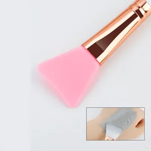 Détail pinceau masque facial en silicone, tête rose douce avec manche or rose pour soin de peau.