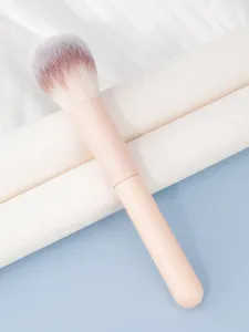 Primer plano de brocha de maquillaje rosa suave con cerdas degradadas para polvo y colorete.
