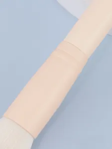 Detailfoto van de make-upkwast, zachte witte haren en beige handvat voor een nauwkeurige make-up.