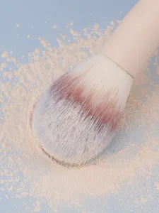 Primer plano detallado de brocha de maquillaje suave con cerdas densas y polvo cosmético fino.