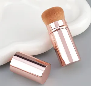 Detailed shot of a portable rose gold makeup brush with soft bristles and protective cap.