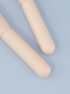 Oversized skin-colored makeup brush handle detail view, professional cosmetic tool display.
