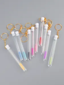 Detailansicht Wimpernbürste im transparenten Röhrchen mit goldenem Schlüsselanhänger, bunt.