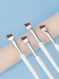 Close-up detail shot of angled eyeliner and eyebrow makeup brushes with sleek white handles.
