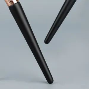 Close-up of professional makeup brush with matte black handle and rose gold ferrule detail.