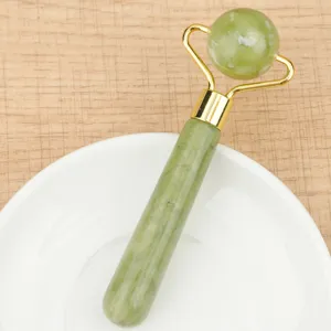 Detail view of a green jade facial roller with a spherical head and golden metal bracket.