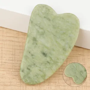Green jade stone gua sha facial tool detail view, natural mineral texture massage scraping.