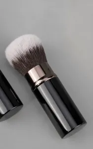 Retractable makeup brush detail view, soft synthetic bristles, portable cosmetic tool for travel.