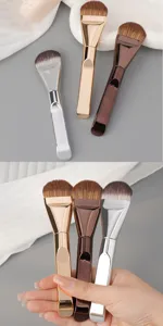 Detail shot of tongue-shaped foundation brushes with metallic handles in silver, gold, and brown.