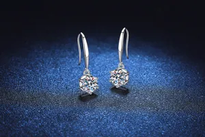 Primer plano de pendientes colgantes brillantes de plata con detalles de piedra moisanita.
