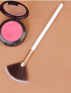 Detail shot of a soft bristle fan makeup brush with white handle and golden ferrule for highlighting.