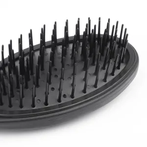 Close-up detail of black hairbrush bristle pad, flexible cushion and pins for scalp massage.