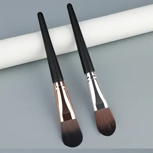 Close up of professional tongue shaped foundation brush and makeup tool with wooden handle.