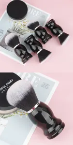 Close-up detail of black handle large round makeup brush, soft synthetic fibers for powder.