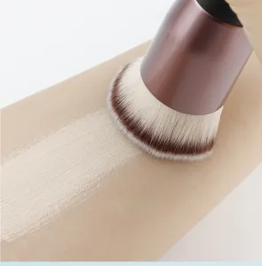Detail shot of a dense flat top foundation brush applying liquid makeup smoothly on skin.