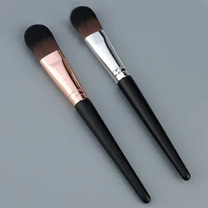 Detail view of tongue-shaped foundation makeup brush with wooden handle and metal ferrule.