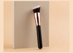 Vista detallada de una brocha de maquillaje grande y biselada con cerdas sintéticas suaves.