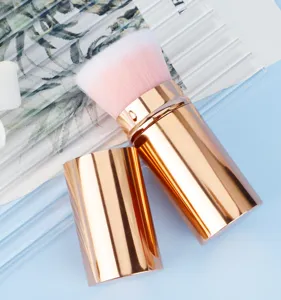 Portable retractable makeup brush close-up detail with rose gold case and soft pink bristles.