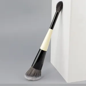 Gros plan détaillé sur le pinceau de maquillage à double embout professionnel aux poils doux.