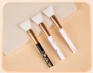 Kit de pinceaux pour masque facial en silicone avec poignées marbrées et férule dorée.