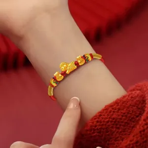 Detalle de pulsera roja del zodiaco chino con dije de caballo de oro y bolsas de la fortuna.