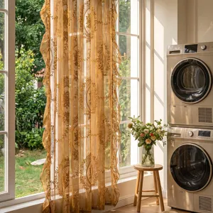 Rideau transparent brodé doré luxueux avec volants délicats pour un salon élégant.