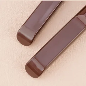 Detail shot of brown handle flat foundation brush makeup tool, smooth finish design.