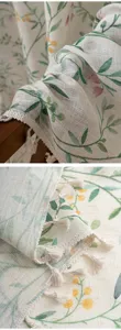 Close-up detail of pastoral style linen curtain with floral leaf print and cute tassel fringe.