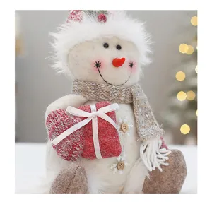 Nahaufnahme des niedlichen Weihnachtsplüschschneemanns mit rotem Geschenkbox-Ornament.