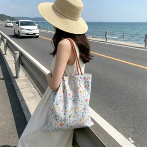 Detailaufnahme der bestickten Segeltuch-Tasche mit Blumenmotiv in malerischer Küstenumgebung.