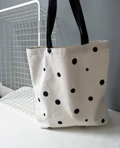 Vista dettagliata della borsa in tela minimalista con pois neri e comodi manici.