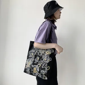 Details of black canvas tote bag with cute bear print, stylish daily shoulder bag for women.