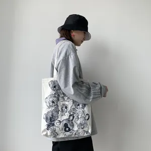 Detail view of canvas tote bag with vintage bear illustration on shoulder of model.
