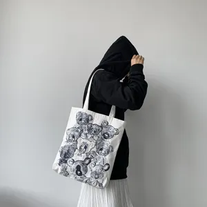 Canvas tote bag detail showing cute hand-drawn teddy bear print and comfortable long shoulder strap.