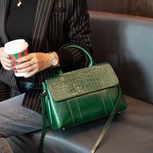 Detailed shot of green crocodile embossed leather shoulder bag in stylish lifestyle setting.