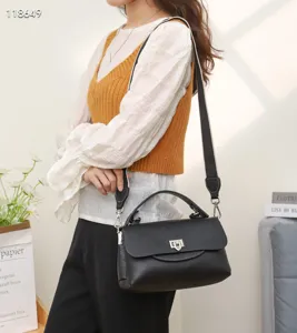 Detailed view of women's black genuine leather handbag with top handle and wide strap.