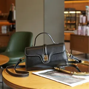 Elegant black leather top-handle crossbody bag with vintage design and metallic clasp.